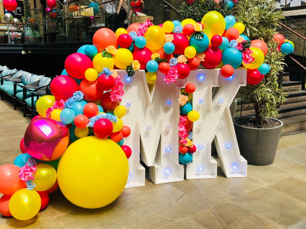 Michael Kors Summer party decoration, MK light up letters with a balloon and flower organic arch. 